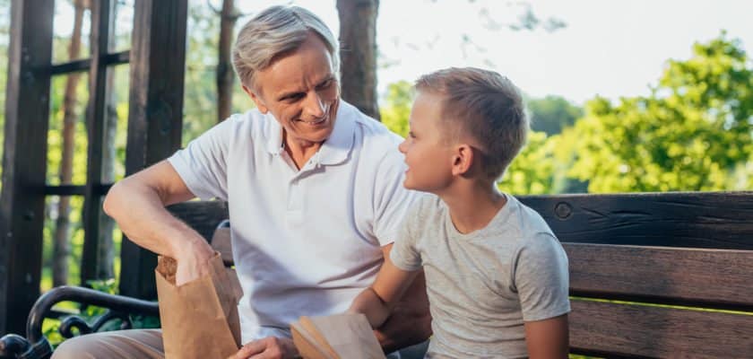 Older adult and boy eating a snack on a bench