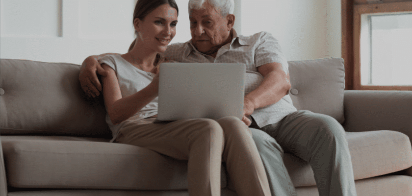 Father talking to daughter on couch looking at laptop