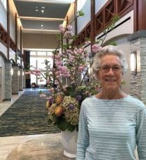 Jane standing in lobby in front of flowers
