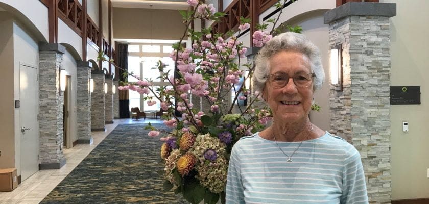 Jane standing in lobby in front of flowers