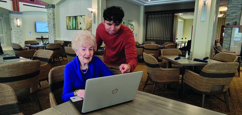 lady at desk with computer with tech helping her