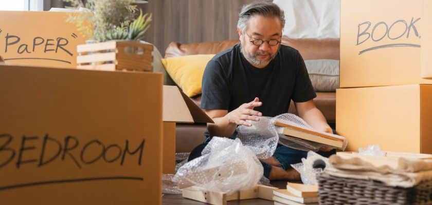 man sitting on floor packing boxes