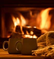 Steam from a cups with a hot cocoa on the fireplace background.