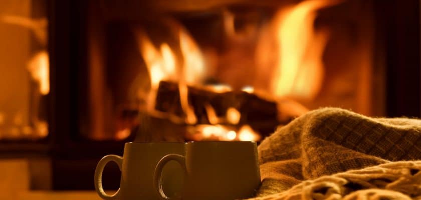 Steam from a cups with a hot cocoa on the fireplace background.